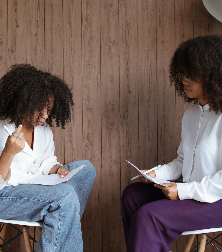 Two women sitting across from each other and working with paper and pencil